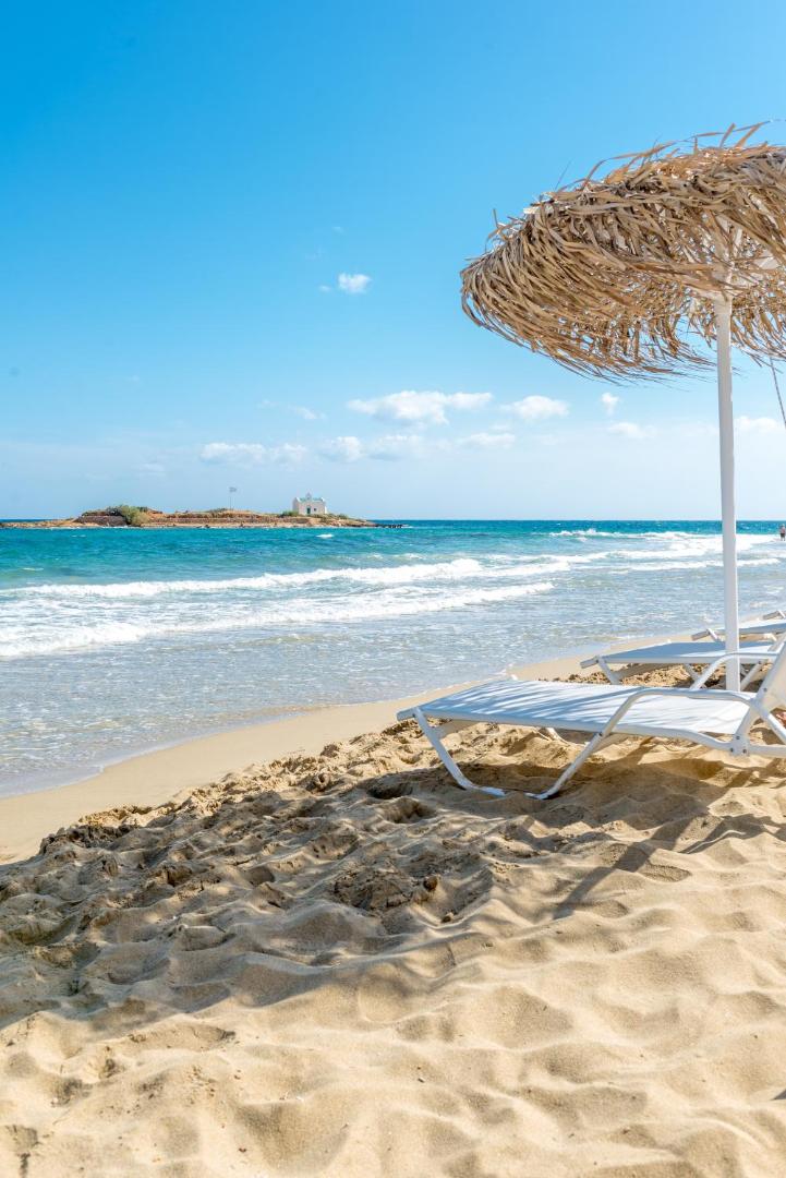 Enorme Ammos Beach Resort pludmales zona ar baltiem sauļošanās krēsliem un salmu saulessargiem pie dzidra jūras ūdens Malijā