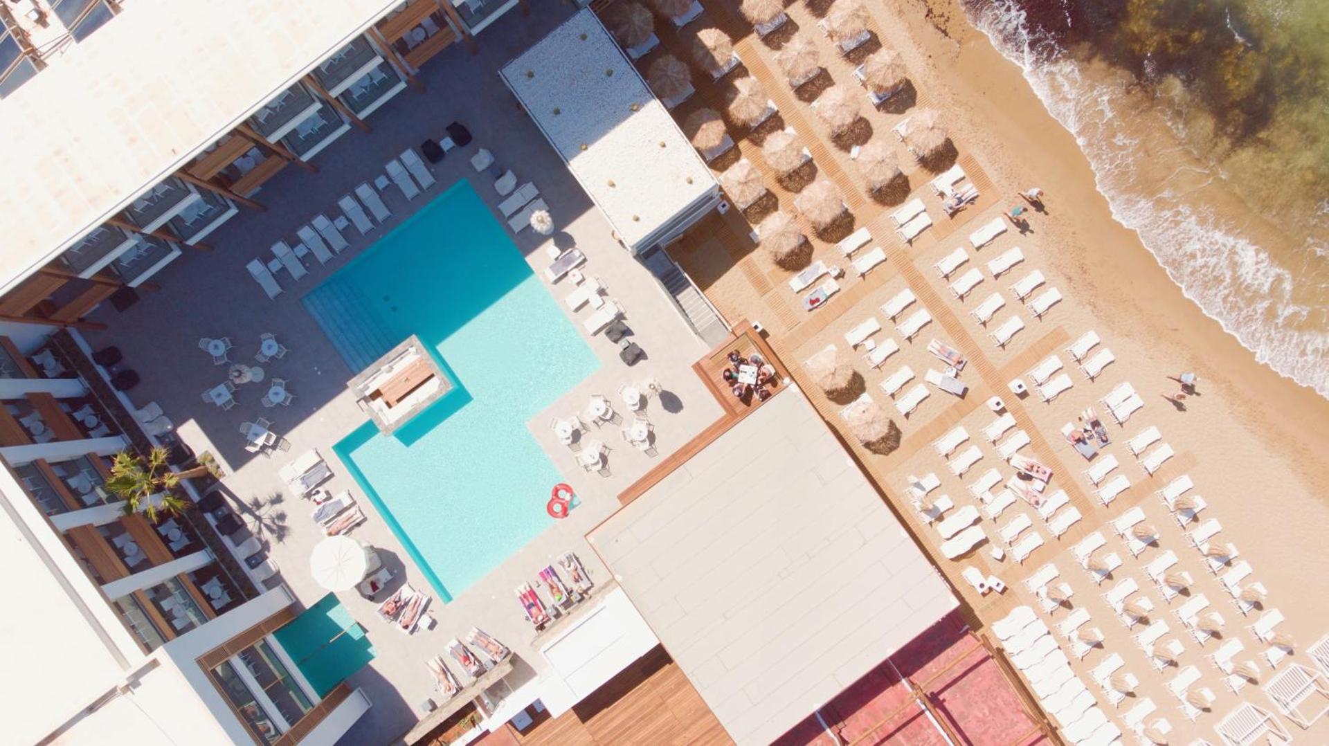 Aerofoto skats uz Enorme Ammos Beach Resort baseinu un privāto smilšu pludmali Malijā, Krētā — saulessargi un gultas pie jūras