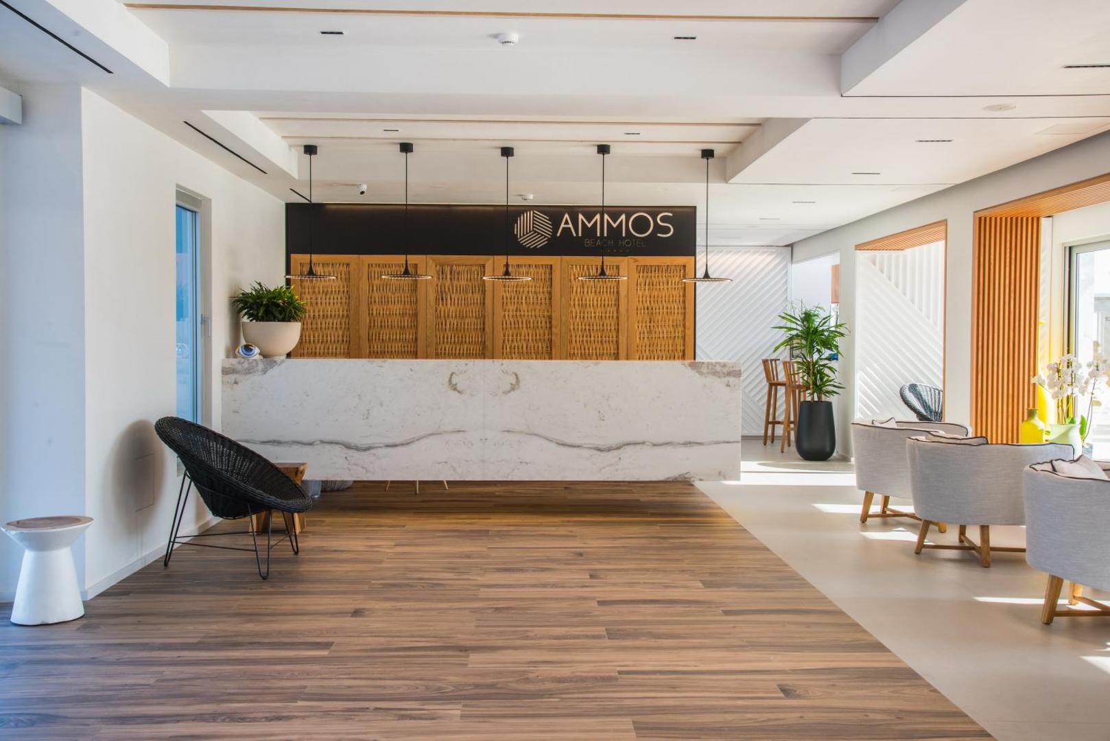 Enorme Ammos Beach Resort reģistratūras lete ar marmora apdari un koka sienas paneļiem gaišā, modernā viesnīcas vestibilā