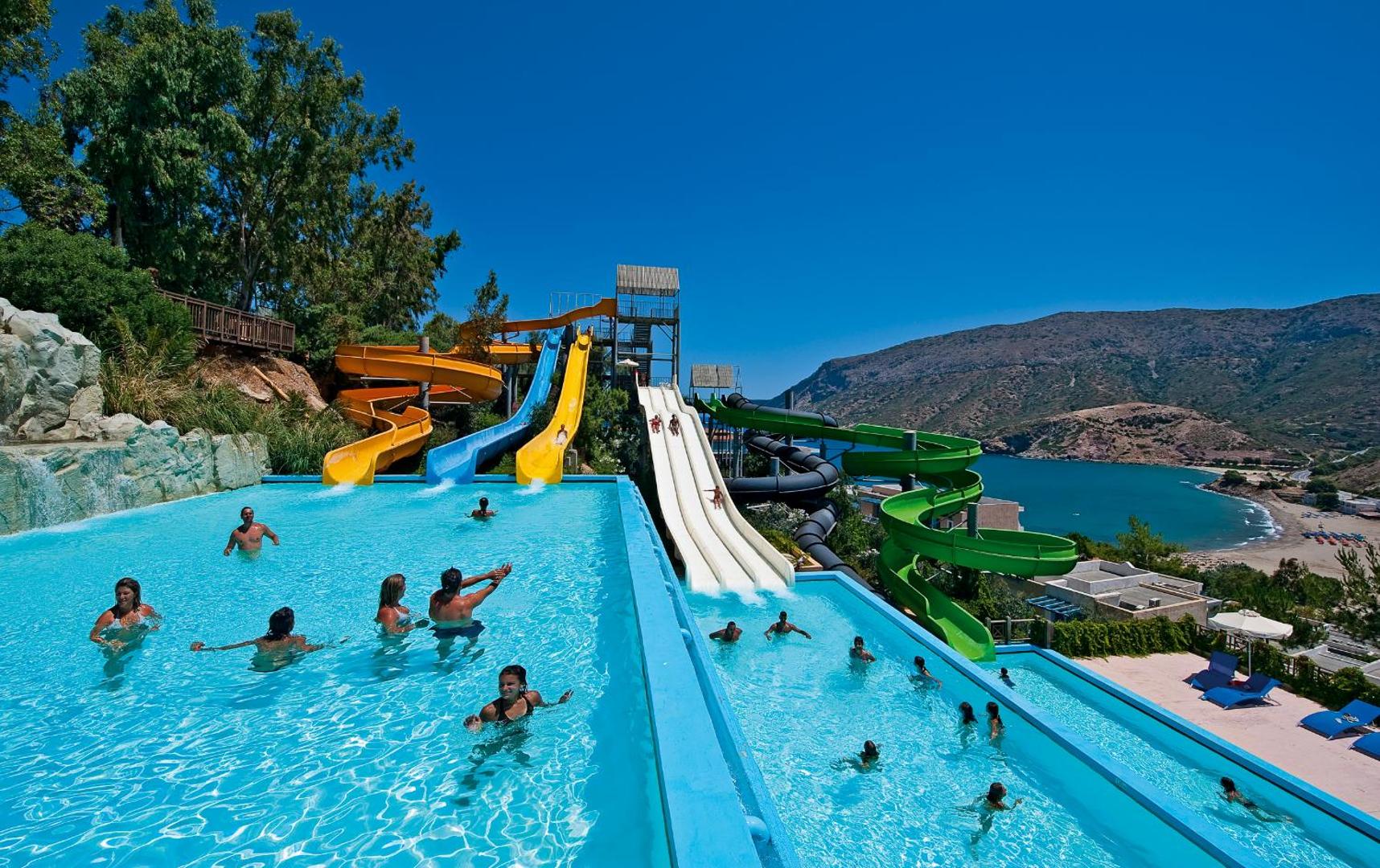 Fodele Beach & Water Park Resort akvaparks ar krāsainiem slidkalniņiem un baseinu piekrastē ar skatu uz jūru