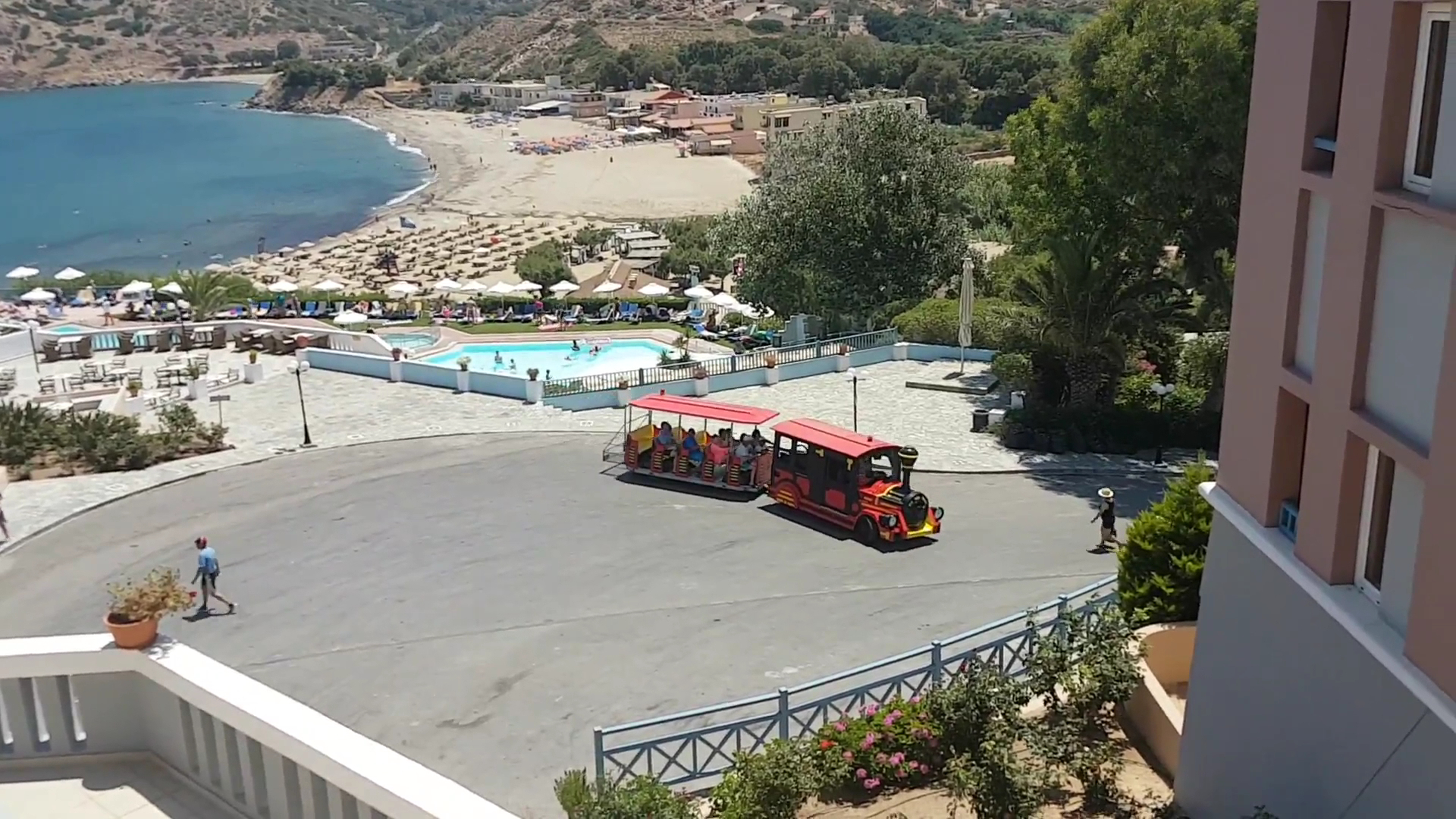 Skats no augšas uz Fodele Beach kūrorta teritoriju, tūristu vilcieniņu, baseinu un smilšu pludmali līča piekrastē Krētā