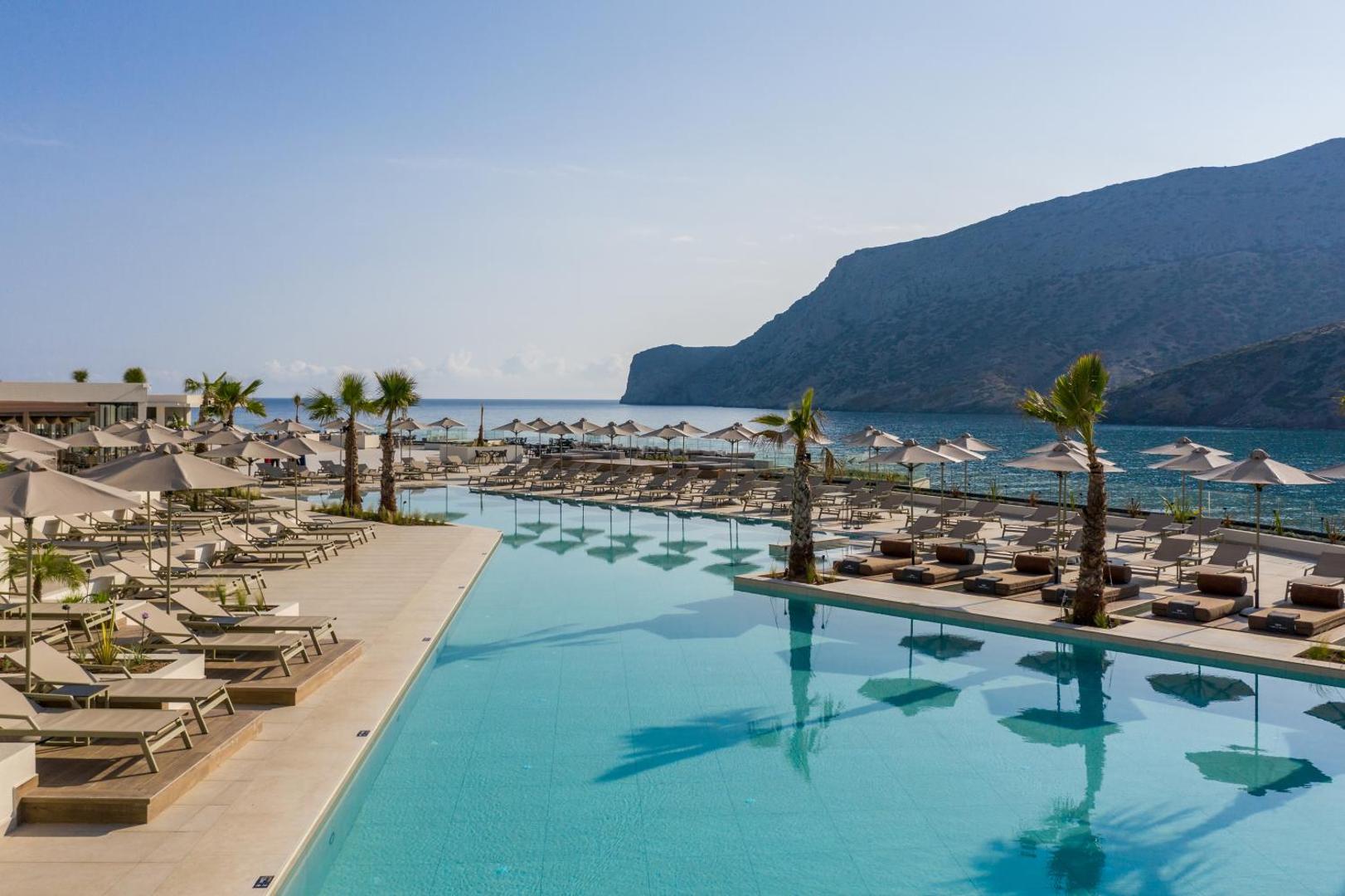Fodele Beach & Water Park Resort āra baseins ar sauļošanās krēsliem, saulessargiem un skatu uz kalniem un līci