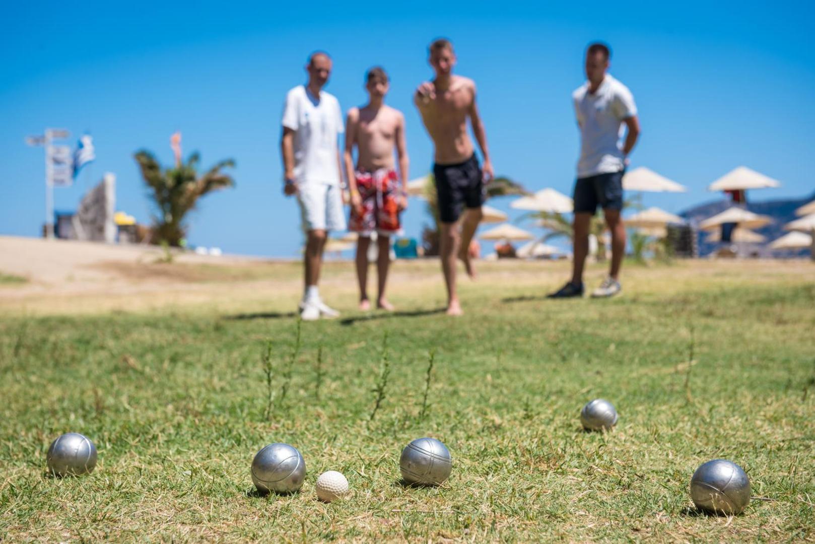 Viesi spēlē boči zālienā netālu no pludmales Fodele Beach & Water Park Resort kūrortā saulainā dienā