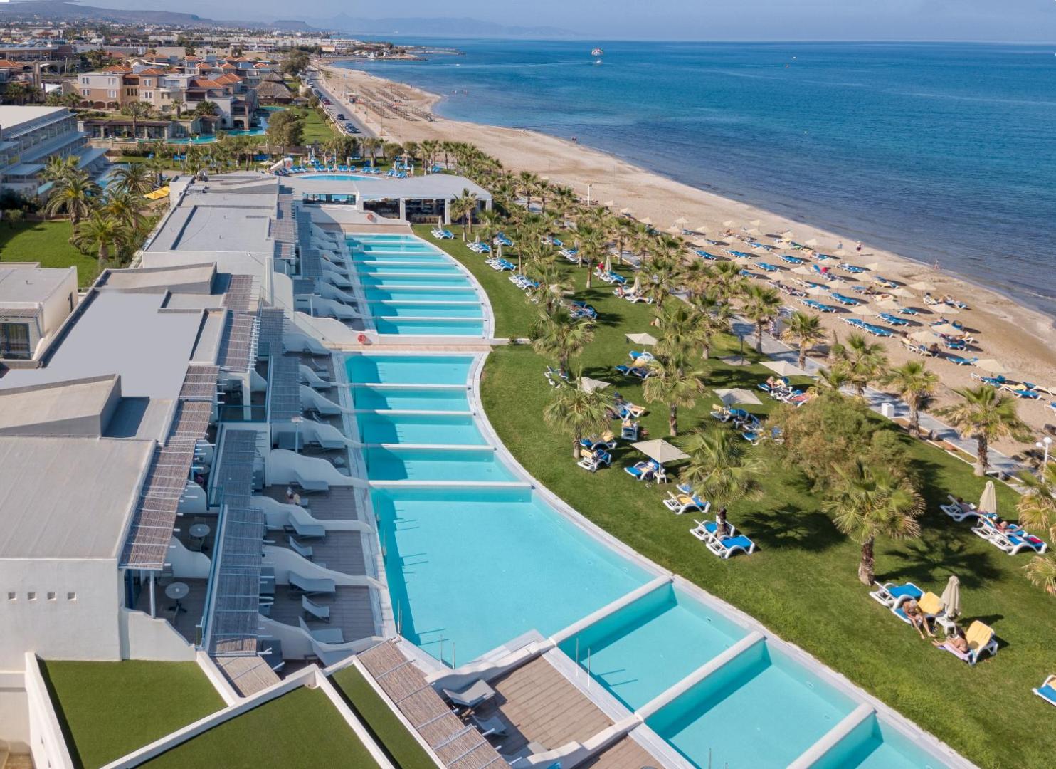 Lyttos Beach numuri ar privātiem baseiniem un skatu uz jūru — koplietošanas zāliens ar sauļošanās krēsliem un palmām