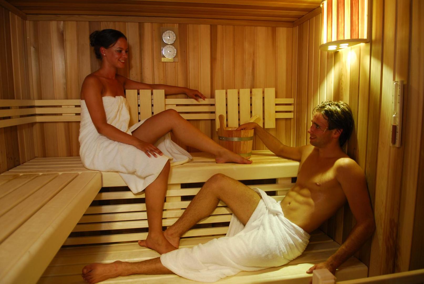 Viesnīcas Cactus Beach koka apdares sauna ar diviem atpūtniekiem, radot siltu un relaksējošu spa pieredzi