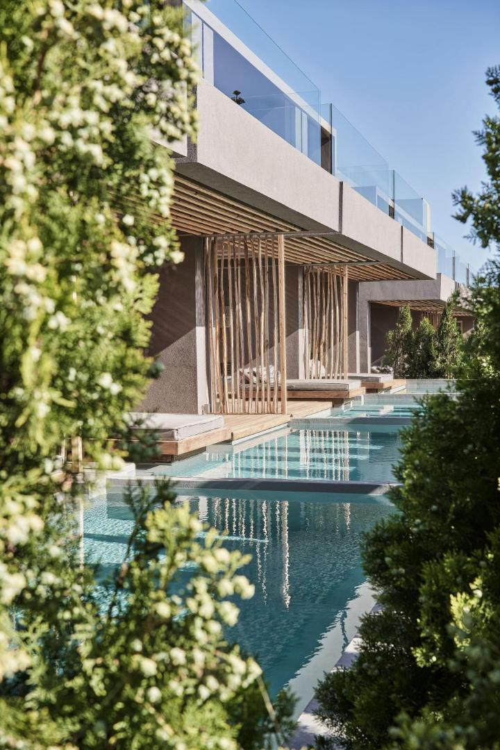 NEMA Design Hotel & Spa modernā arhitektūra ar baseinu rindu un stikla balkoniem, ko ieskauj dekoratīvie apstādījumi