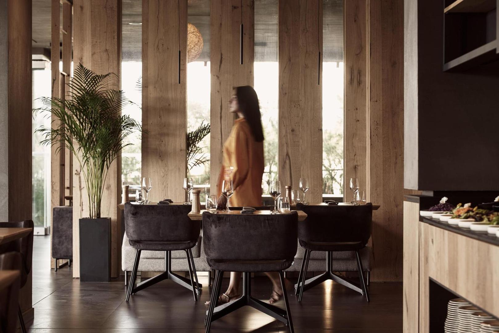 NEMA Design Hotel & Spa restorāna interjers ar koka paneļiem, moderniem krēsliem un servētiem galdiem vakariņām
