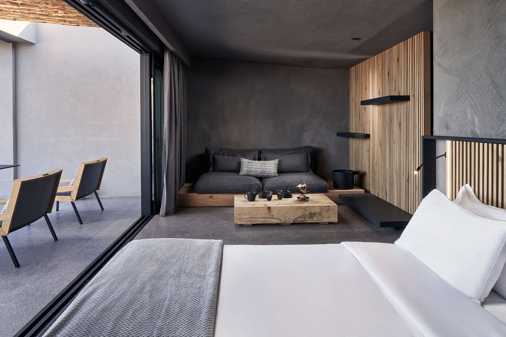 NEMA Design Hotel & Spa numura interjers ar skatu uz balkonu, kurā izvietoti ērti krēsli un koka dizaina elementi.