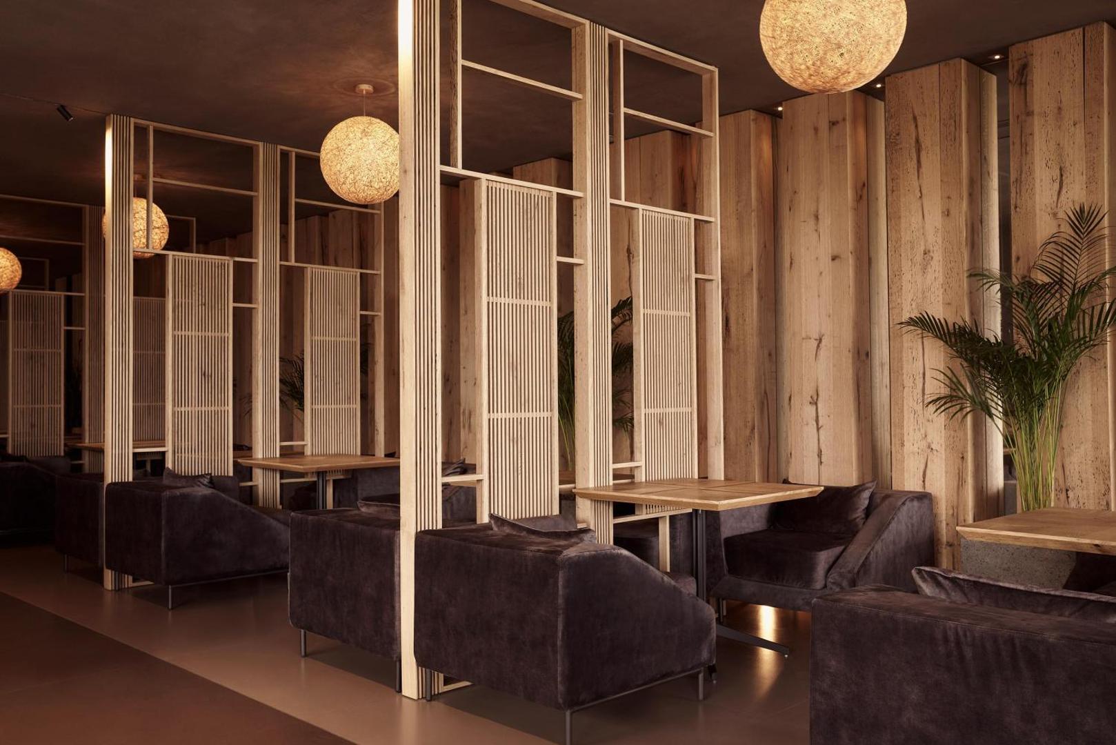 NEMA Design Hotel & Spa elegants iekštelpu bārs un atpūtas zona ar koka apdari, mīkstiem krēsliem un dizaina gaismekļiem
