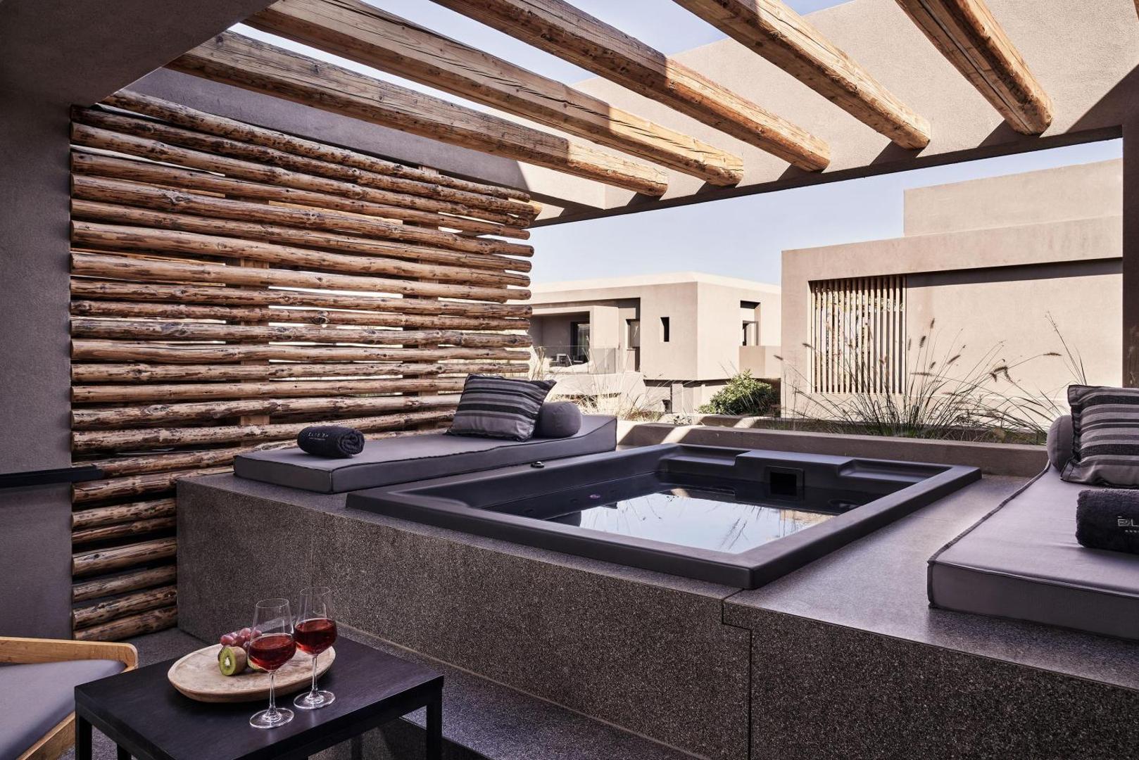 NEMA Design Hotel & Spa numura terase ar privātu džakuzi, atpūtas krēsliem un vīna glāzēm uz galdiņa