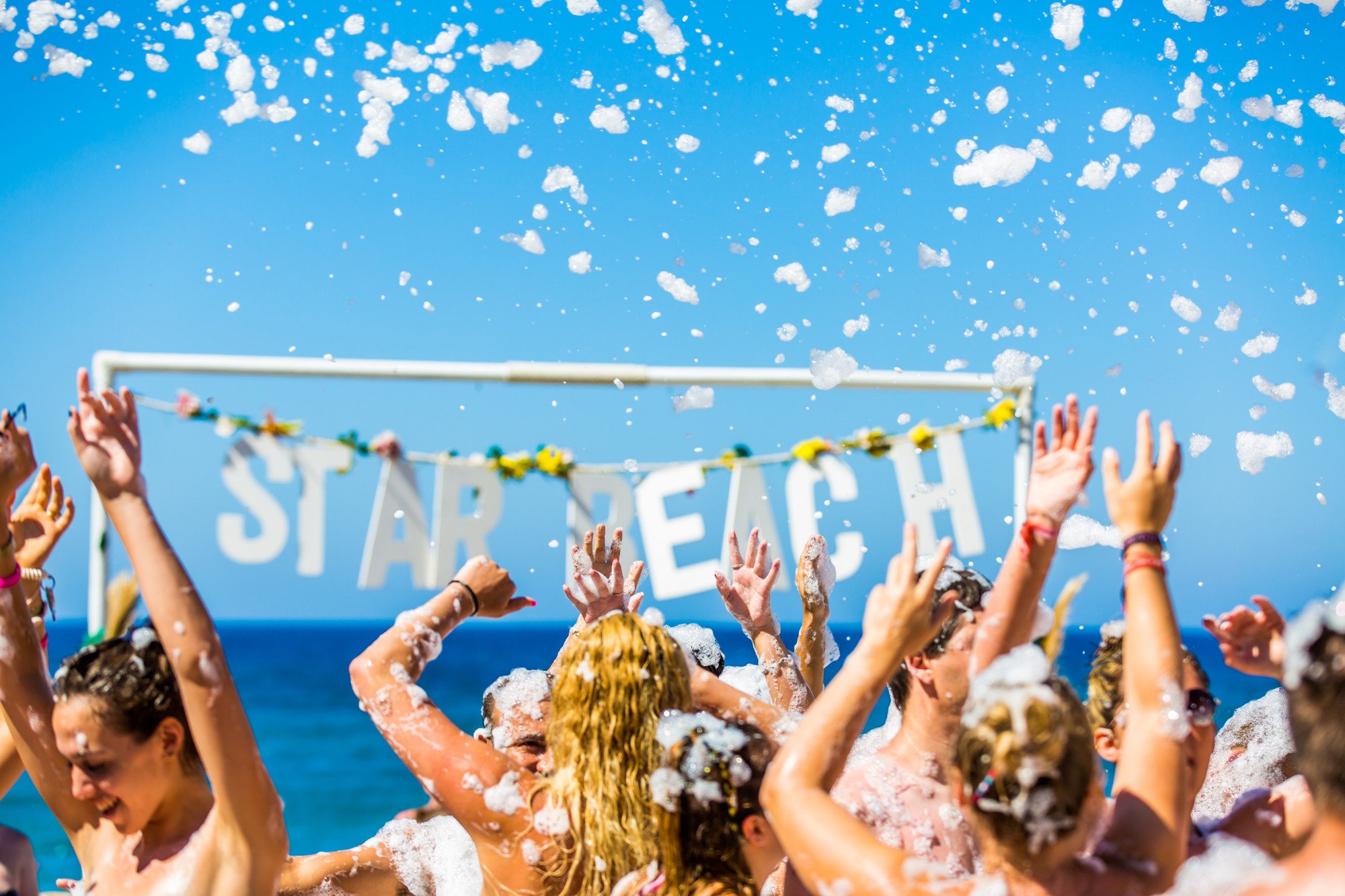 Star Beach Village & Water Park putu ballīte pludmalē Hersonisā, Krētā — jaunieši izklaidējas mūzikas un putu pavadījumā pie jūras