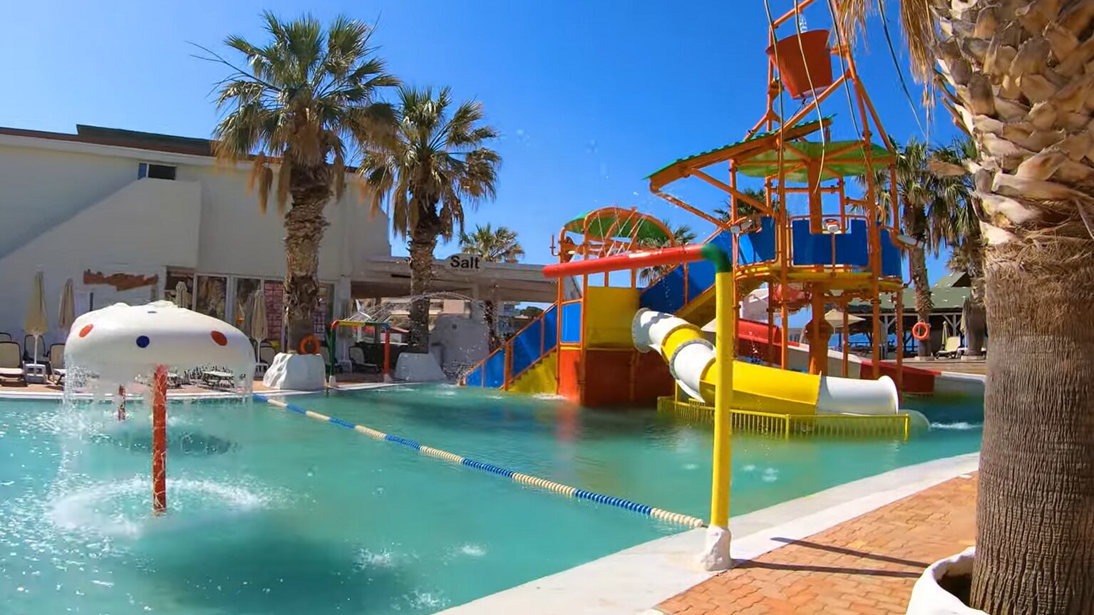 Star Beach Village & Water Park akvaparka zona bērniem ar krāsainiem slidkalniņiem, ūdens sēnīti un palmu ieskautu baseinu