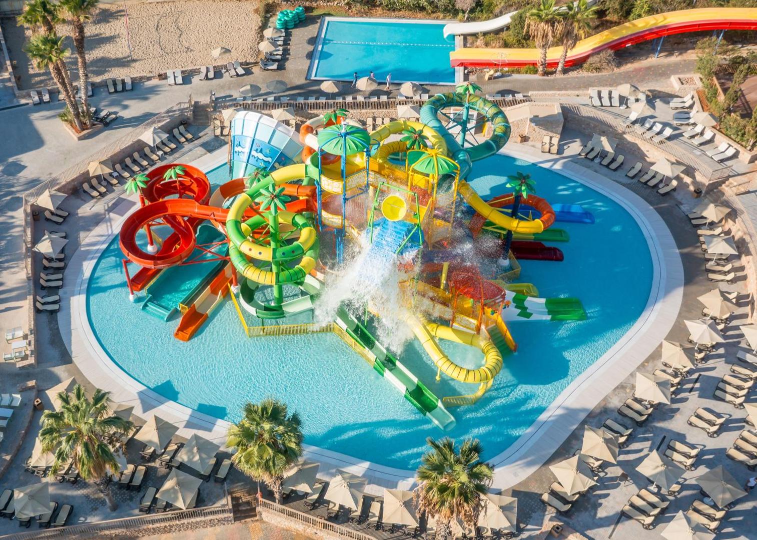 Star Beach Village & Water Park bērnu ūdens atrakciju parks no putna lidojuma — slidkalniņi, baseins un sauļošanās krēsli