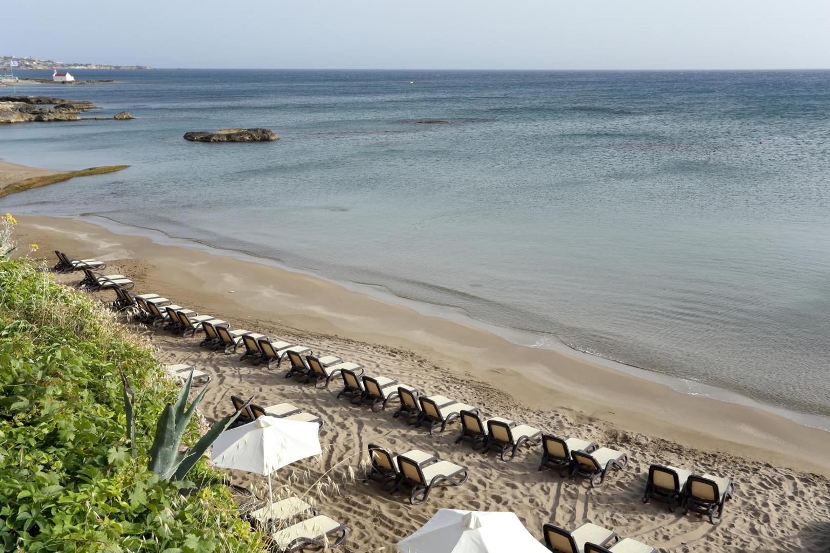 Star Beach Village & Water Park privātā smilšu pludmale ar sauļošanās krēsliem un skatu uz Krētas piekrastes līci