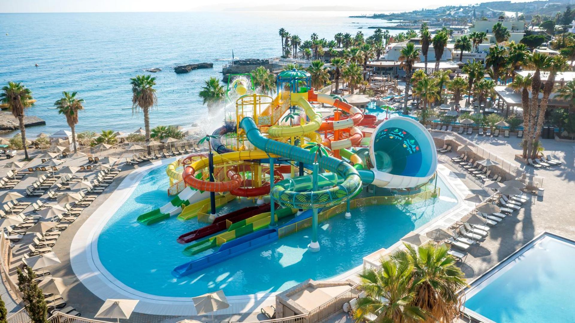 Star Beach Village & Water Park akvaparks pie jūras Hersonisā — krāsaini slidkalniņi, baseini un palmas piekrastē