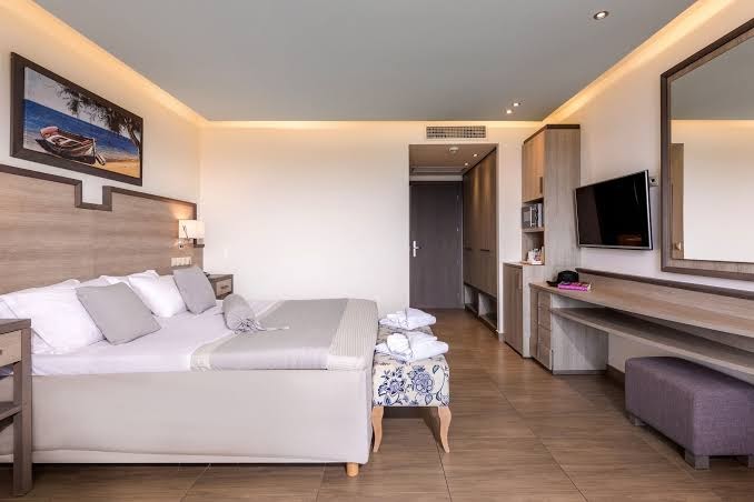 Star Beach Village viesnīcas numura interjers ar divguļamo gultu, koka mēbelēm, televizoru un atpūtas solu Hersonisā