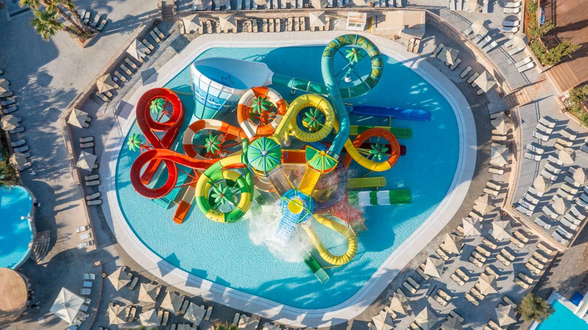 Star Beach Village & Water Park akvaparks Hersonisā, Krētā — skats no augšas uz krāsainiem ūdens slidkalniņiem un baseinu kompleksu
