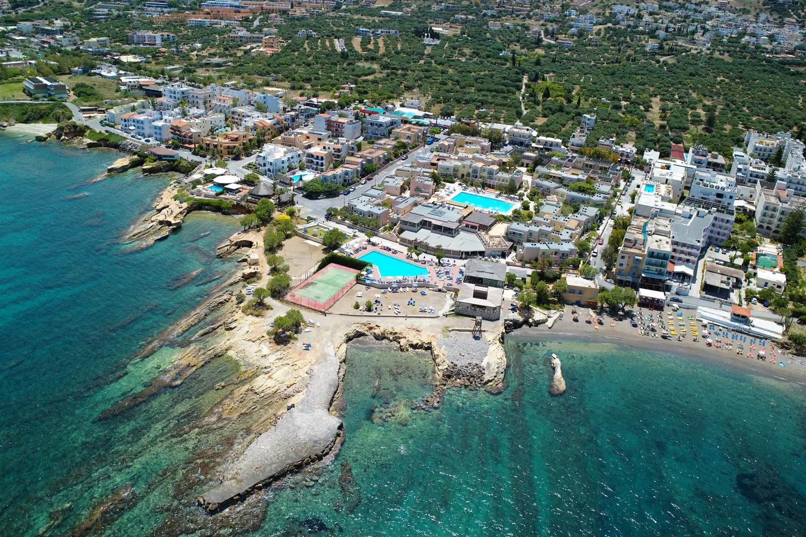 Silva Beach viesnīcas panorāmas skats no putna lidojuma Hersonisā, Krētā — piekrastes apbūve, āra baseini un tenisa korts pie tirkīzzilas jūras