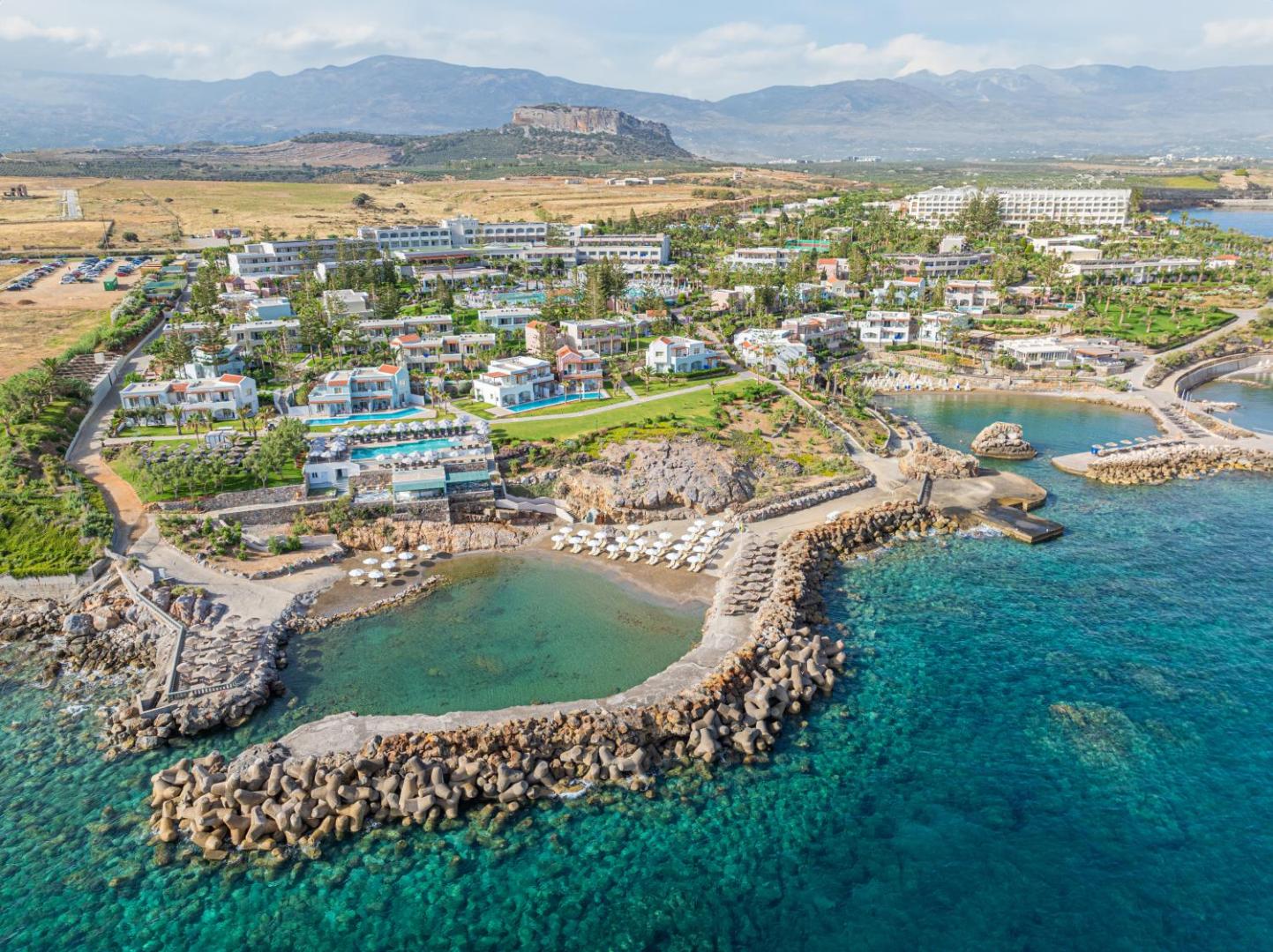 Plašs Iberostar Selection Creta Marine teritorijas skats no putna lidojuma, parādot vairākus līčus, baseinus un viesnīcas ēkas pie jūras.