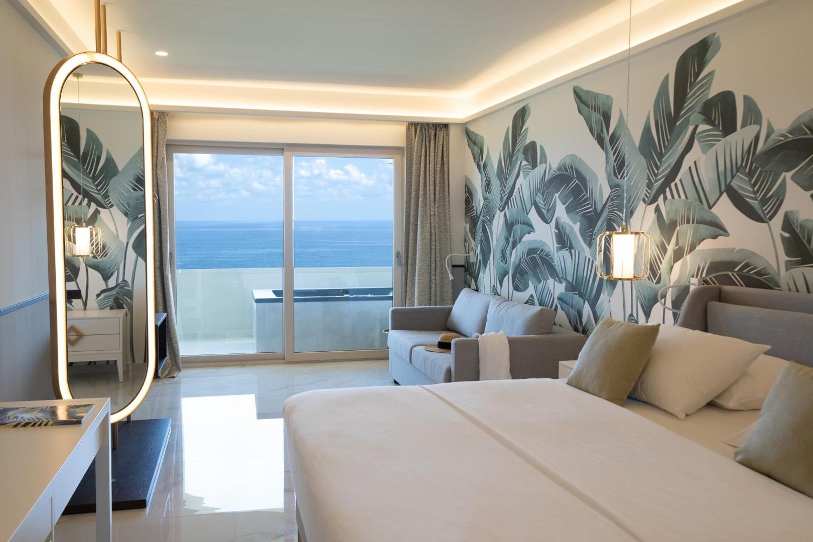 Iberostar Selection Creta Marine moderns numurs ar skatu uz jūru, dīvānu, lielu spoguli un tropisku tapešu dizainu Krētā