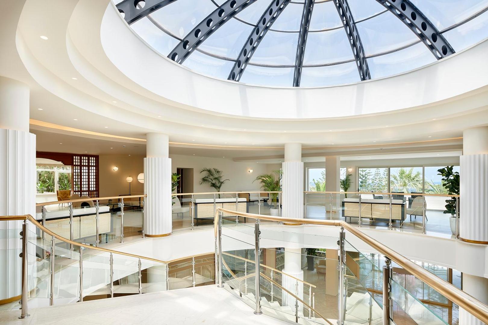 Plašs un gaišs Iberostar Selection Creta Marine lobby ar stikla kupolu, modernām mēbelēm un skatu uz jūru