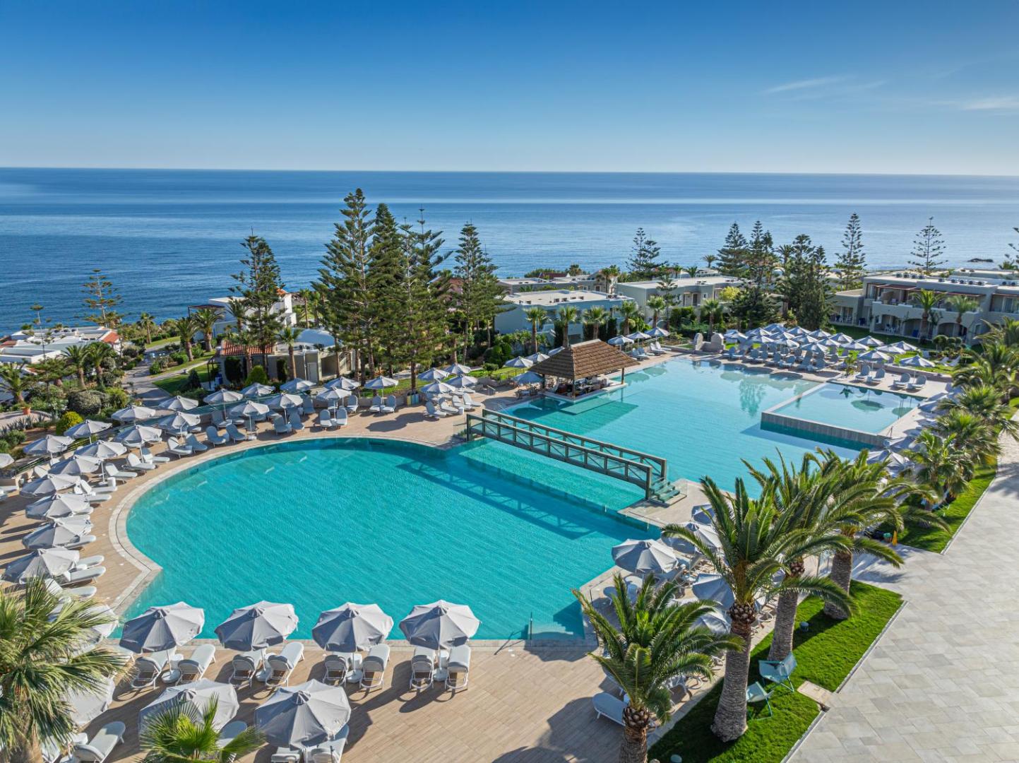 Iberostar Selection Creta Marine plašais āra baseinu komplekss ar skatu uz Vidusjūru Panormas piekrastē, Krētā, saulainā dienā.