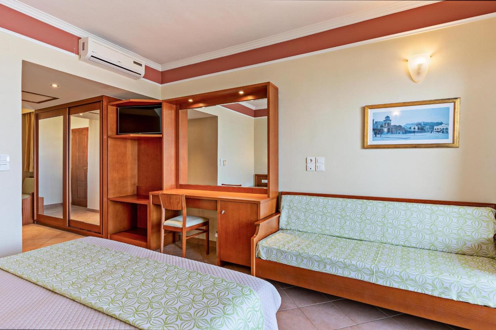 Hydramis Palace Beach Resort numura interjers ar koka mēbelēm, rakstāmgaldu, dīvānu un iebūvēto skapi ar spoguļdurvīm