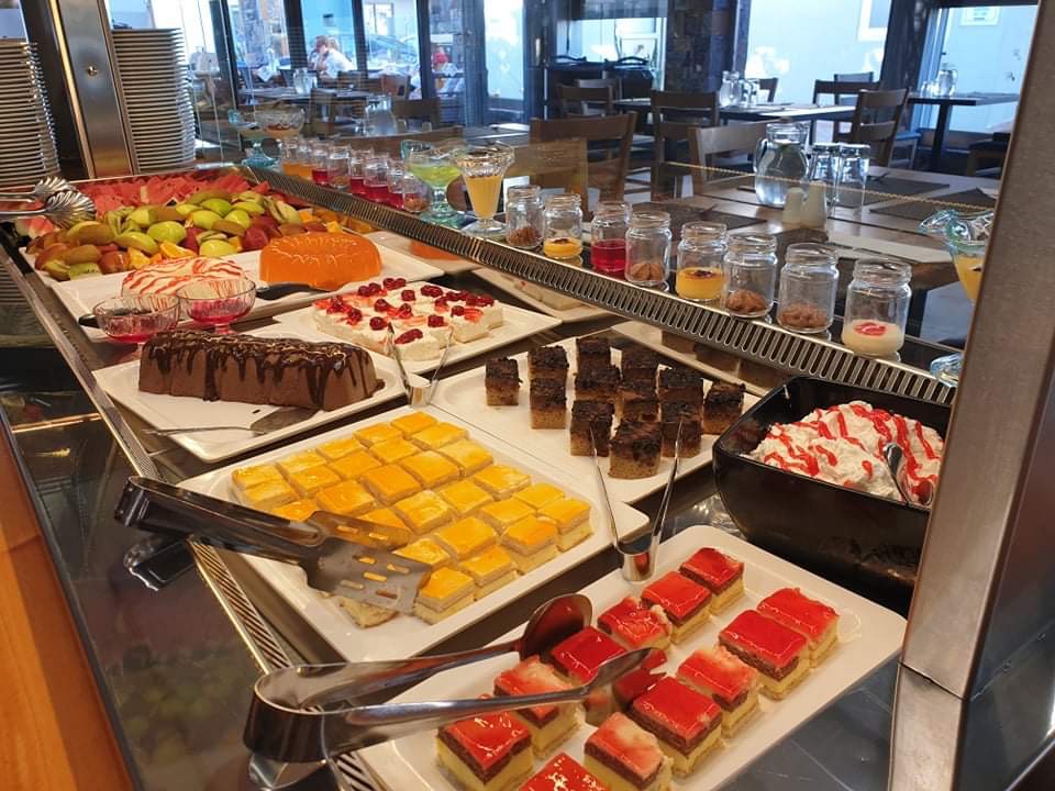 Pollis Hotel desertu bufete ar dažādām kūkām, augļiem un želejām — plaša saldumu izvēle viesnīcas restorānā Hersonisā
