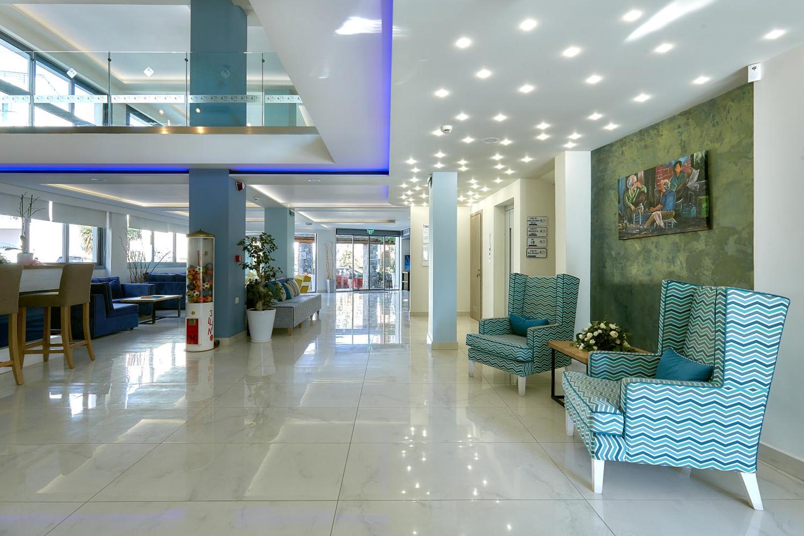 Pollis Hotel viesnīcas vestibils ar rakstainiem atpūtas krēsliem un spīdīgām flīžu grīdām — plaša un gaiša koplietošanas telpa