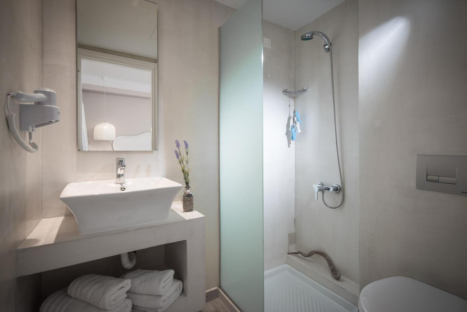 Mari Kristin Beach Hotel numura vannas istaba gaišos toņos — moderna dušas zona, balta izlietne un minimālisma stila dizains