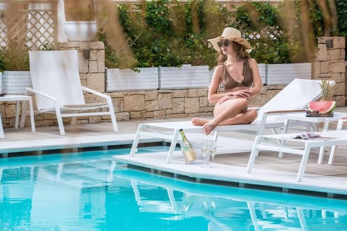 Mari Kristin Beach Hotel saulainā atpūtas zona pie baseina ar moderniem zviļņiem un sievieti peldkostīmā, Hersonisas kūrorts Krētā