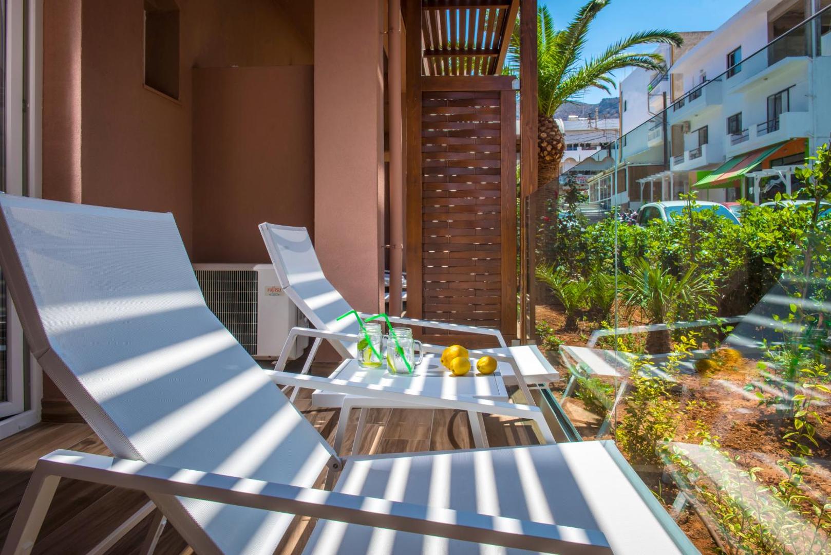 Mari Kristin Beach Hotel numura terase ar diviem sauļošanās krēsliem un atspirdzinošiem dzērieniem Hersonisas kūrortā, Krētā