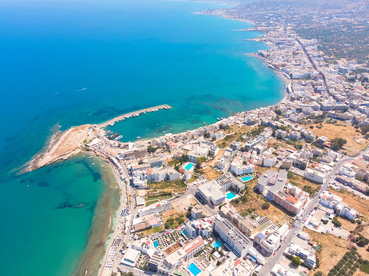 Aerofoto skats uz Hersonisas piekrasti Krētā — Mari Kristin Beach Hotel atrašanās vieta blakus tirkīzzilai jūrai un pilsētas ostai