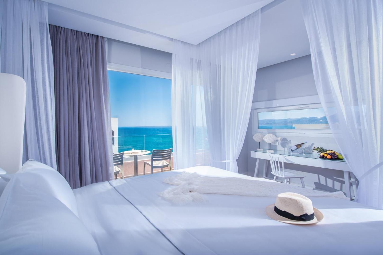 Mari Kristin Beach Hotel gaišs numurs ar skatu uz jūru — balts interjers, liela gulta un balkons ar skatu uz tirkīzzilu ūdeni