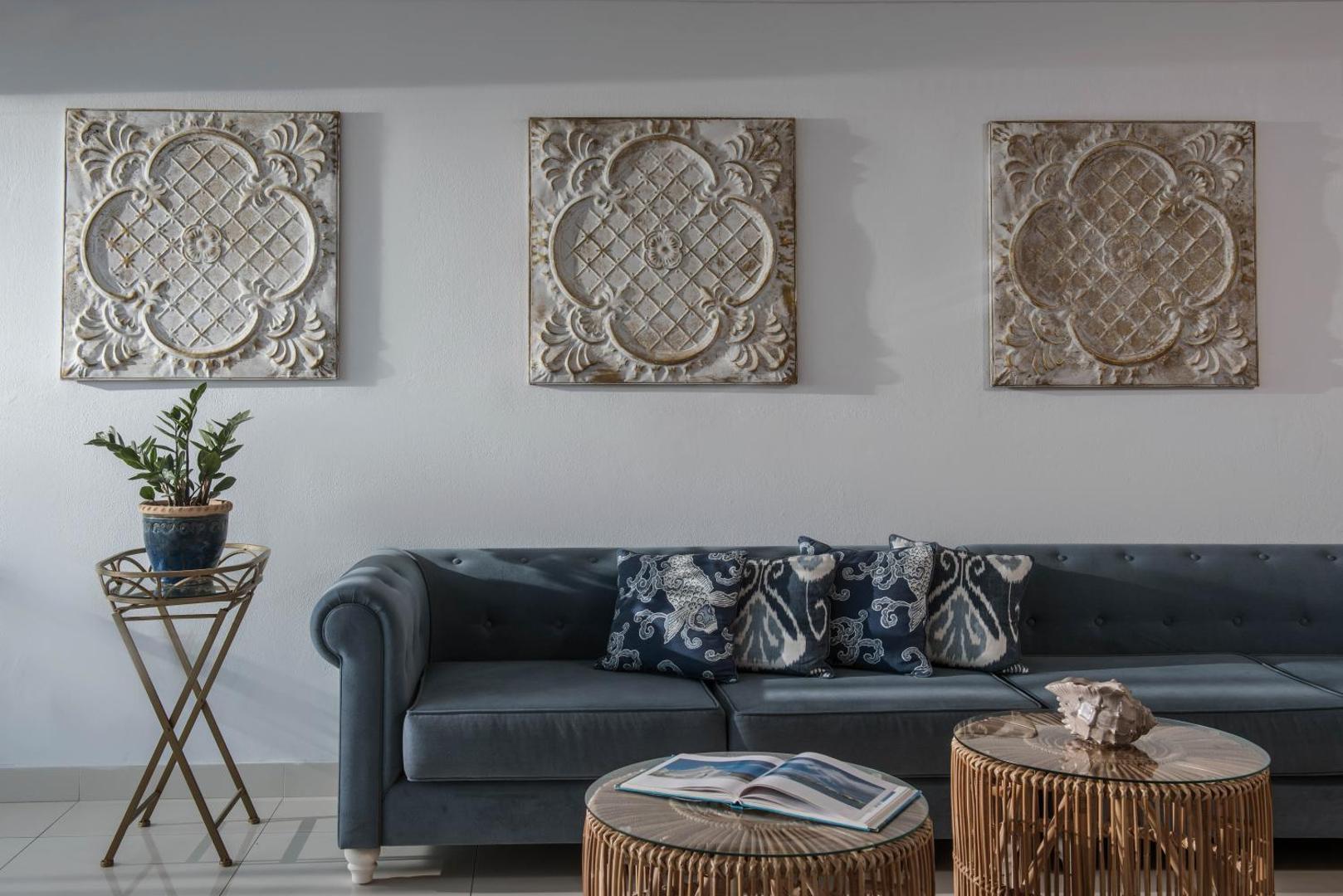 Serenity Spritz Boutique Hotel lobby atpūtas zona ar zilu dīvānu, dekoratīviem spilveniem un sienas mākslas elementiem