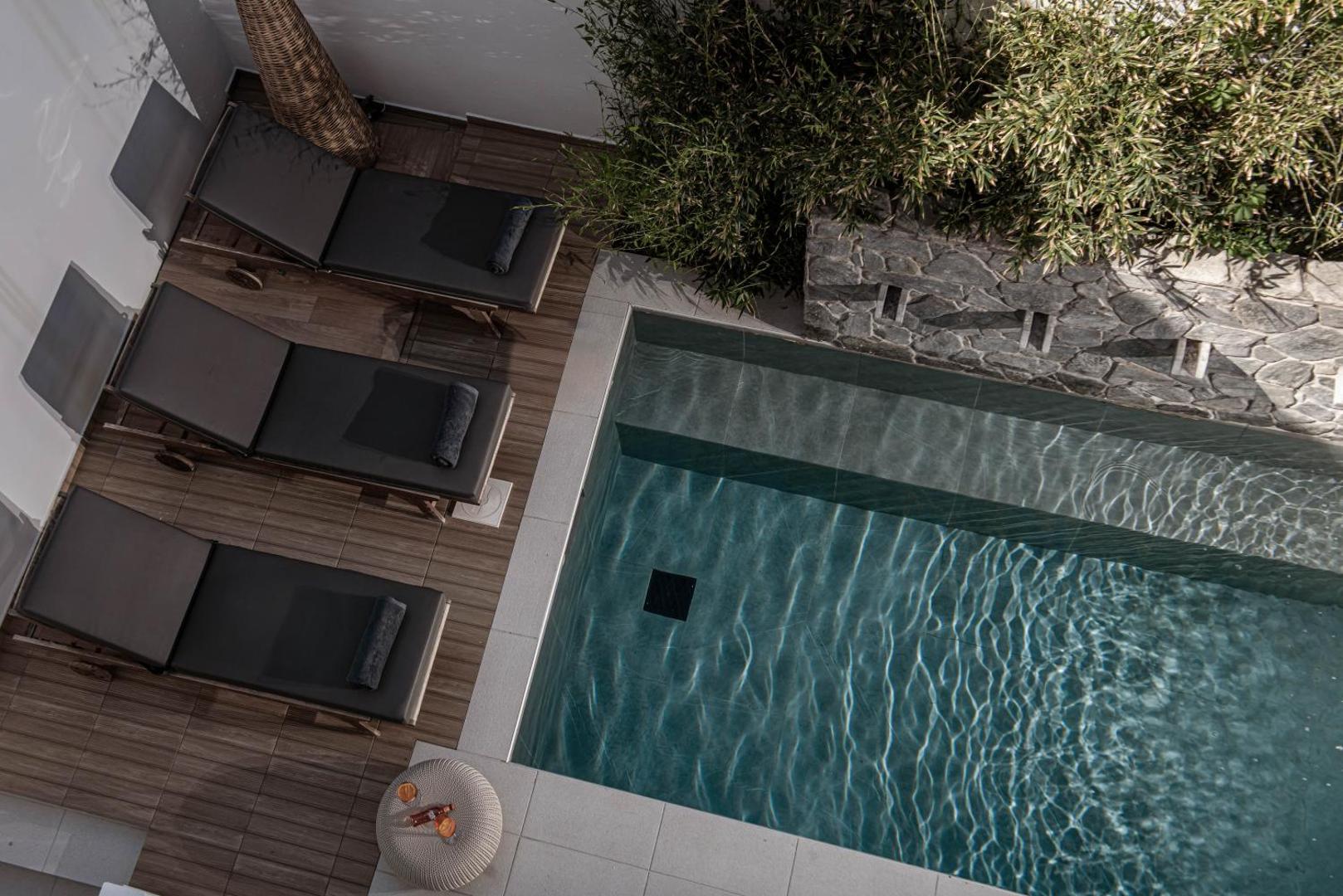 Skats no augšas uz Serenity Spritz Boutique Hotel terasi ar sauļošanās krēsliem un modernu baseinu, ko ieskauj akmens siena un apstādījumi