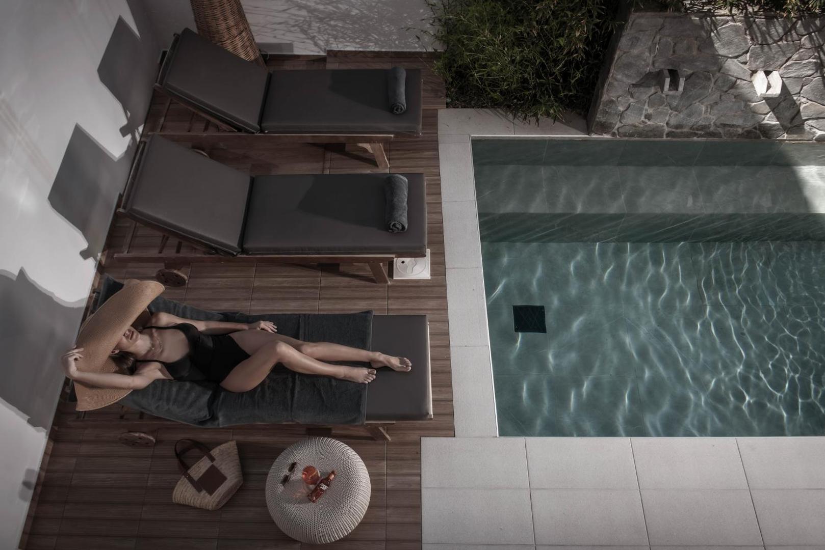 Serenity Spritz Boutique Hotel terase ar sauļošanās krēsliem un baseinu, kurā atpūšas sieviete — moderna arhitektūra un mājīga atmosfēra