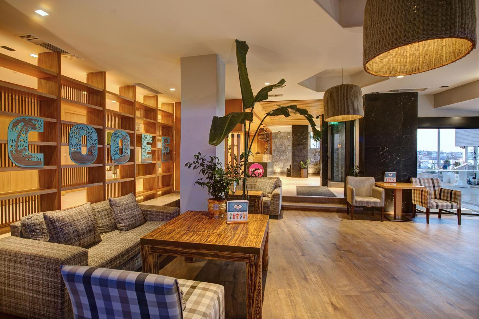 Viesnīcas Palmera Beach Hotel & Spa lobby bāra zona ar stilīgām mēbelēm un dekoratīviem koka elementiem