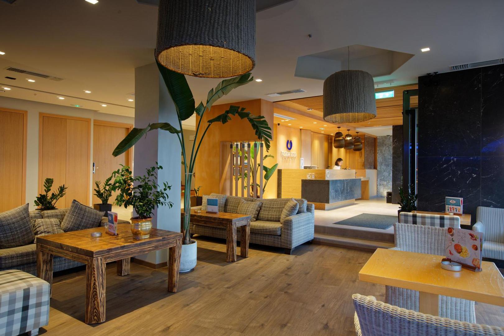 Palmera Beach Hotel & Spa viesnīcas vestibils ar ērtiem dīvāniem, koka galdiem un recepcijas zonu Hersonisā