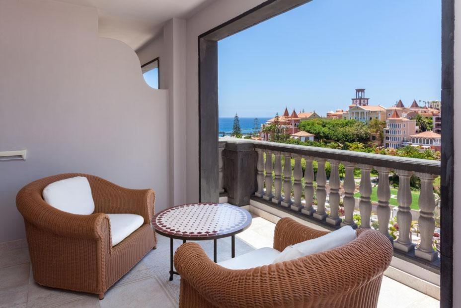 Gran Tacande Wellness & Relax numura balkons ar pītiem krēsliem un skatu uz Tenerifes piekrasti un kaimiņu viesnīcu arhitektūru