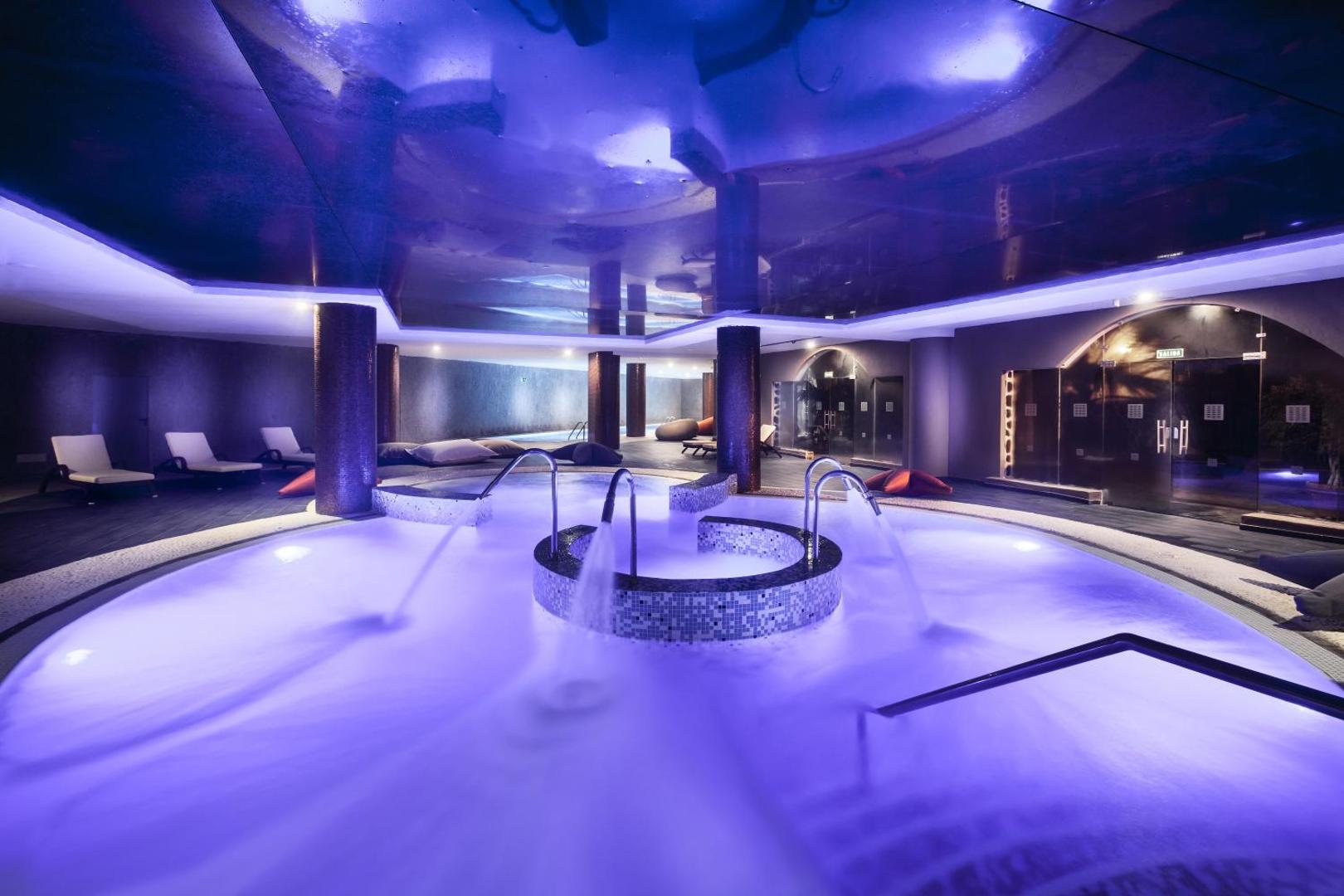 Gran Tacande Wellness & Relax viesnīcas iekštelpu spa baseins ar zilu apgaismojumu, hidromasāžas strūklām un atpūtas krēsliem Tenerifē.