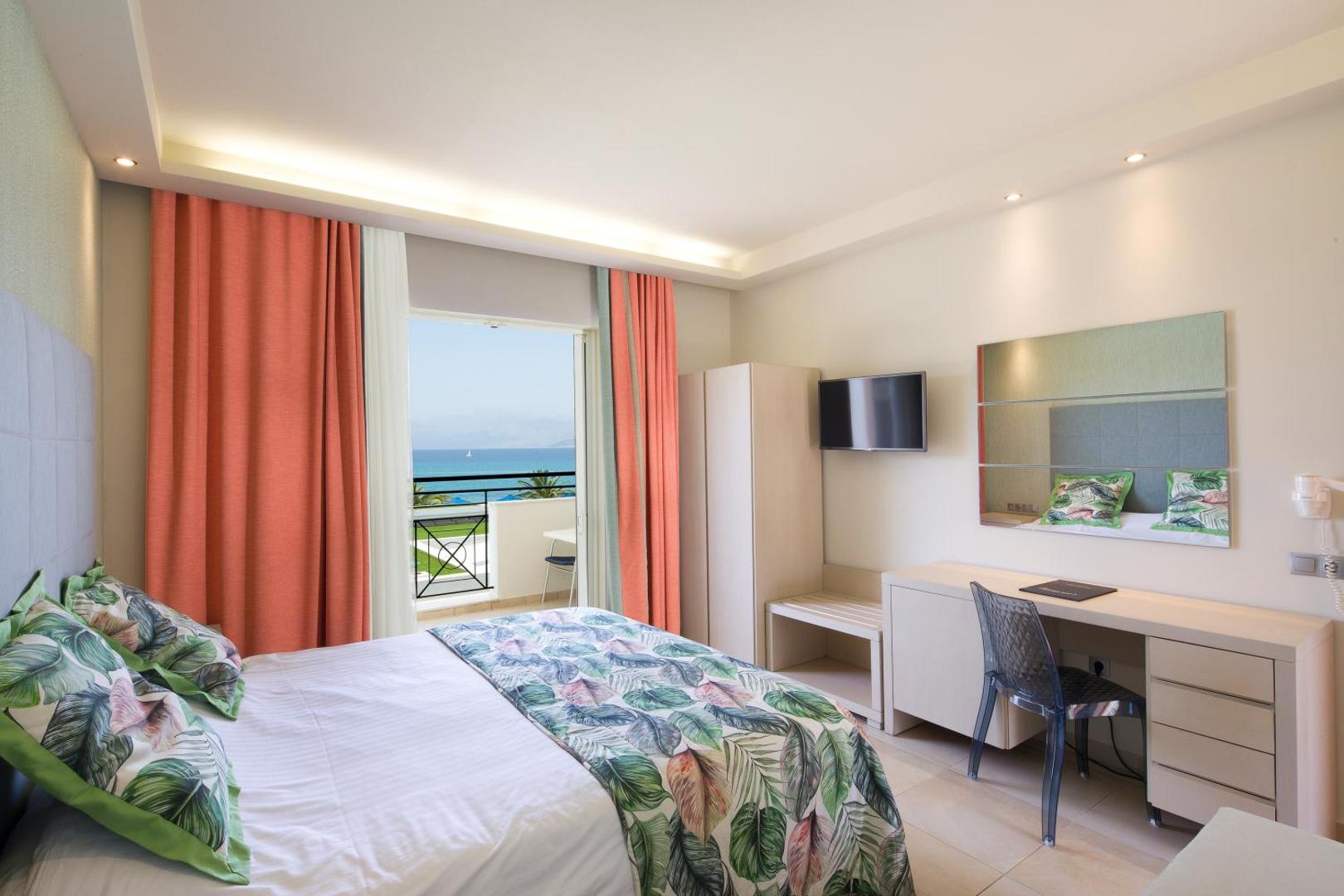 Mareblue Beach Resort plašs numurs ar tropisku rakstu gultas veļu, darba galdu un balkonu ar skatu uz Jonijas jūru.