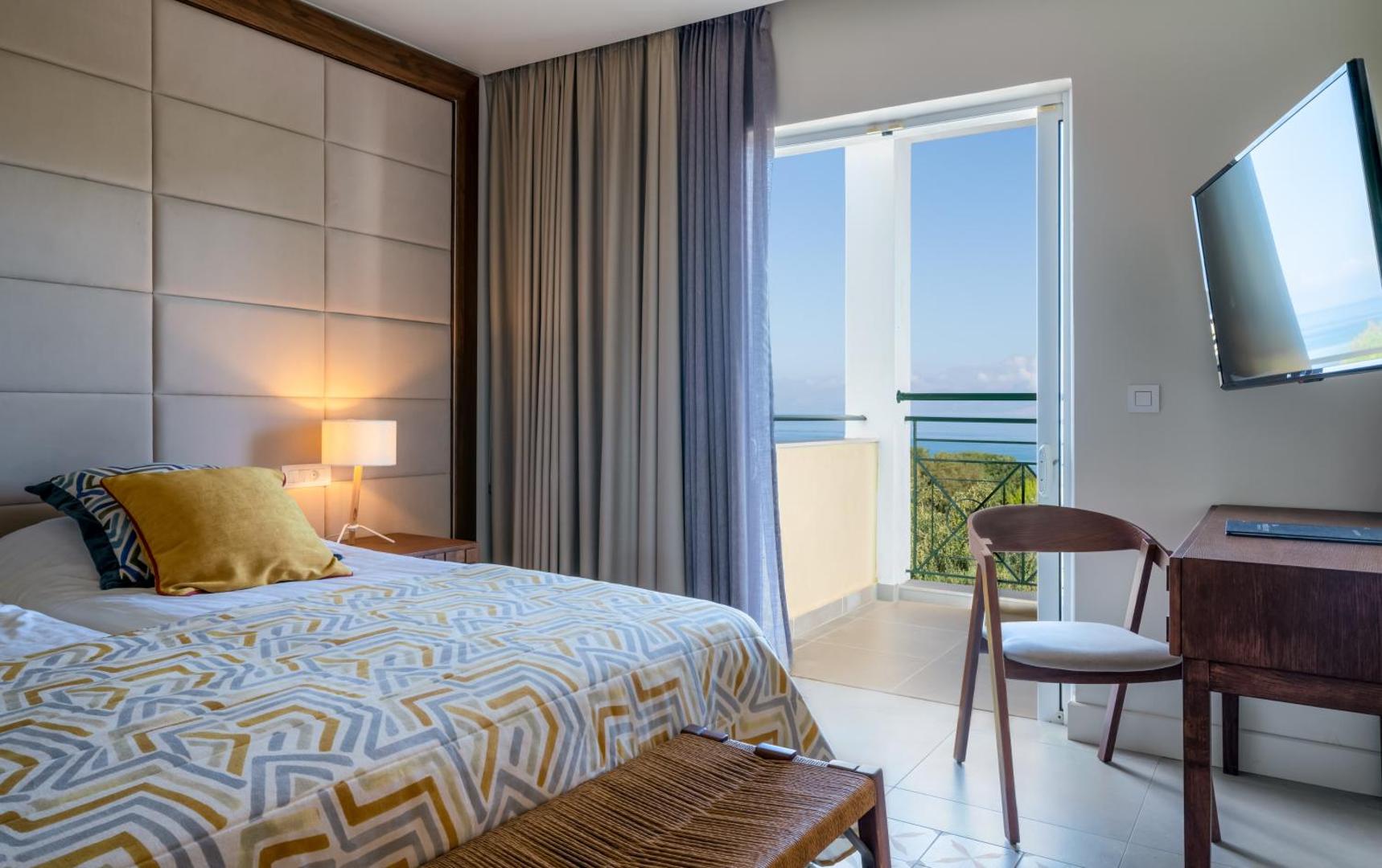 Mareblue Beach Resort gaišs numurs ar balkonu, no kura paveras skats uz dārzu un jūru Korfu piekrastē.