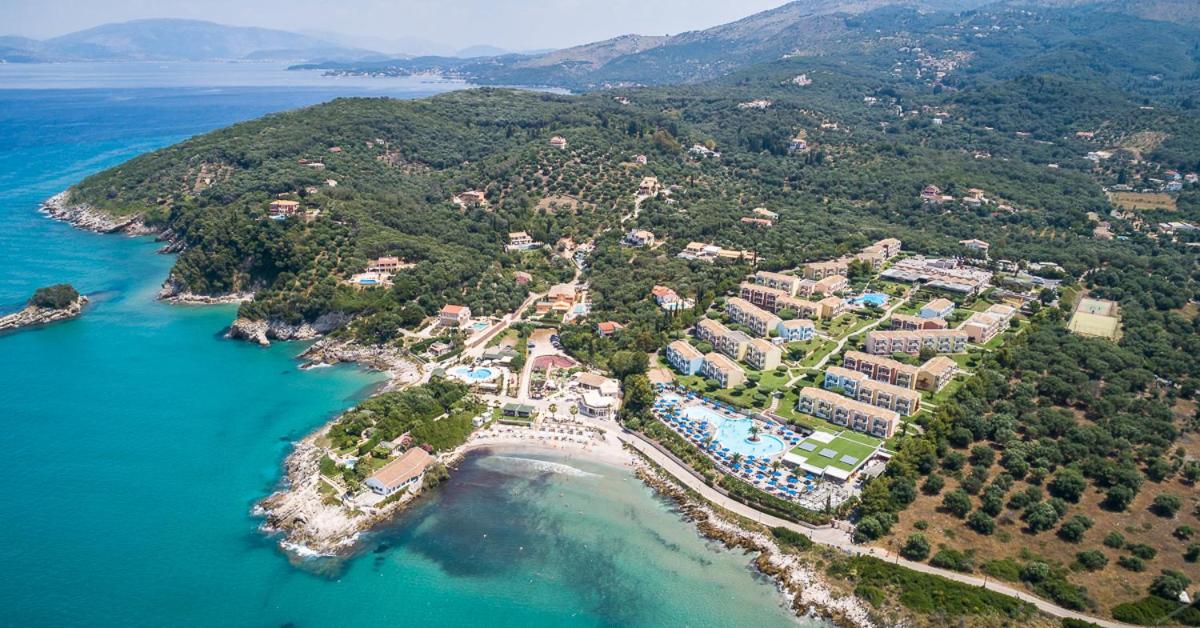 Mareblue Beach Resort panorāmas skats uz Korfu piekrasti, tirkīzzilo Jonijas jūru, pludmali un zaļo kalnu ainavu fonā