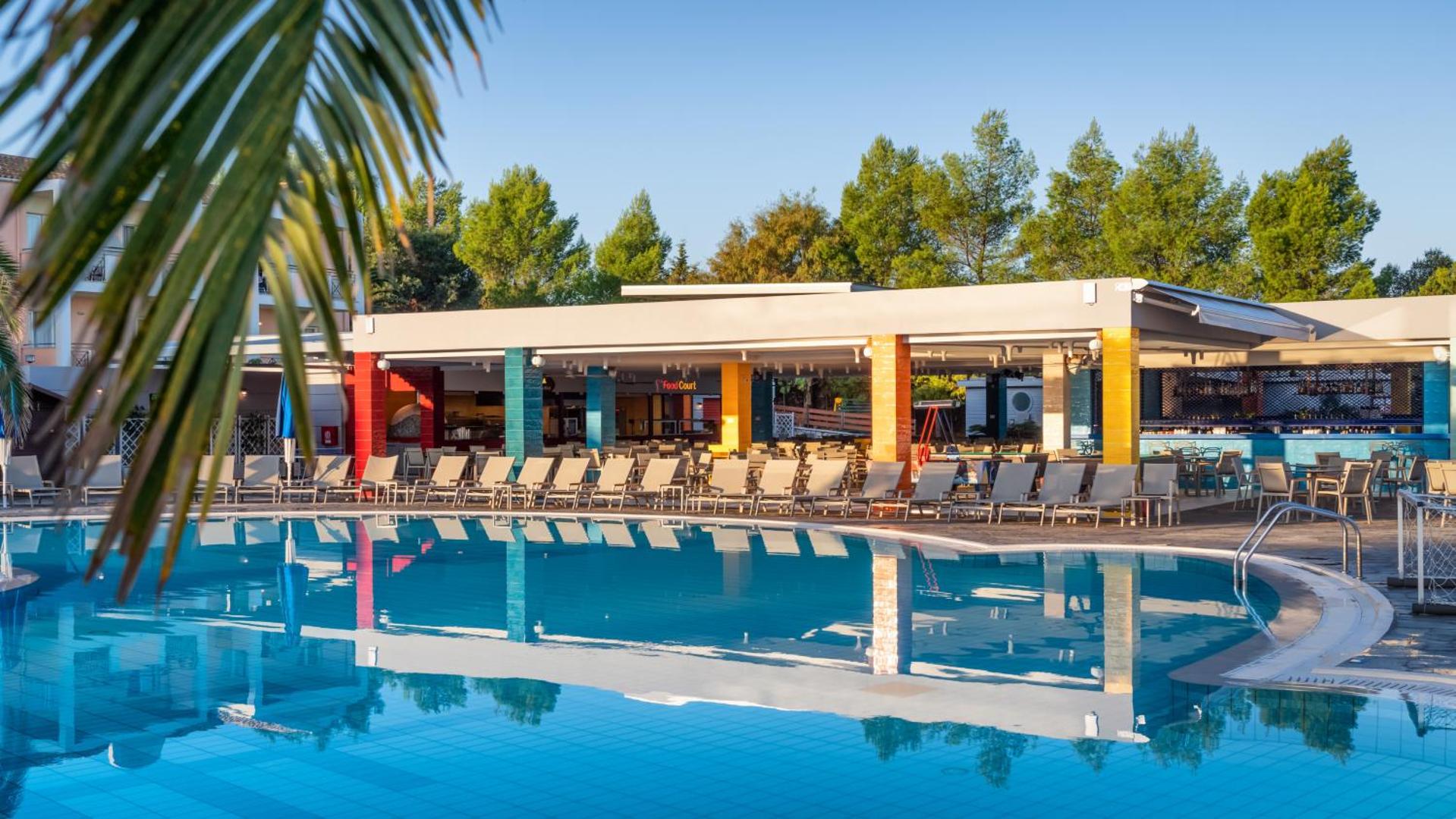 Mareblue Beach Resort baseina bārs un uzkodu zona ar krāsainām kolonnām un sauļošanās krēsliem pie ūdens