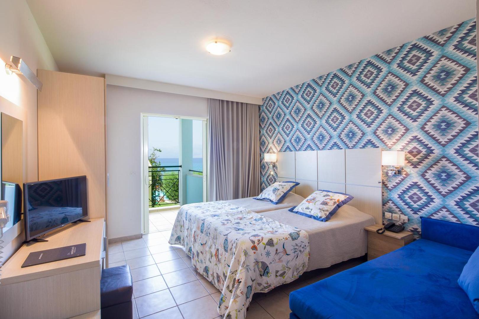 Mareblue Beach Resort numurs ar ziliem akcentiem, divām gultām un balkonu, kas vērsts pret jūras pusi Korfu salā.