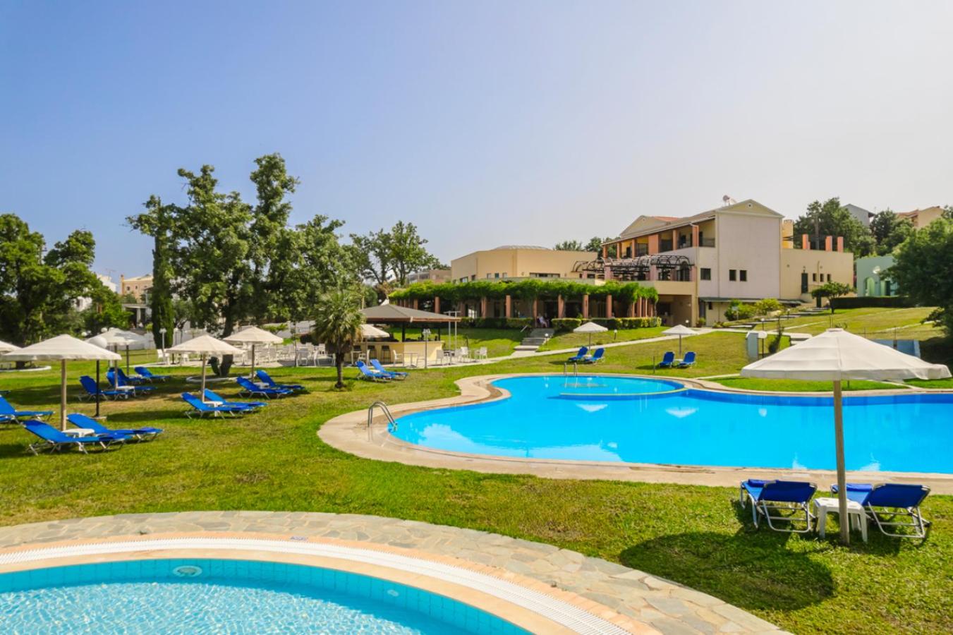 Century Resort Hotel āra baseins dienas laikā ar ziliem sauļošanās krēsliem, saulessargiem un viesnīcas ēku fonā.