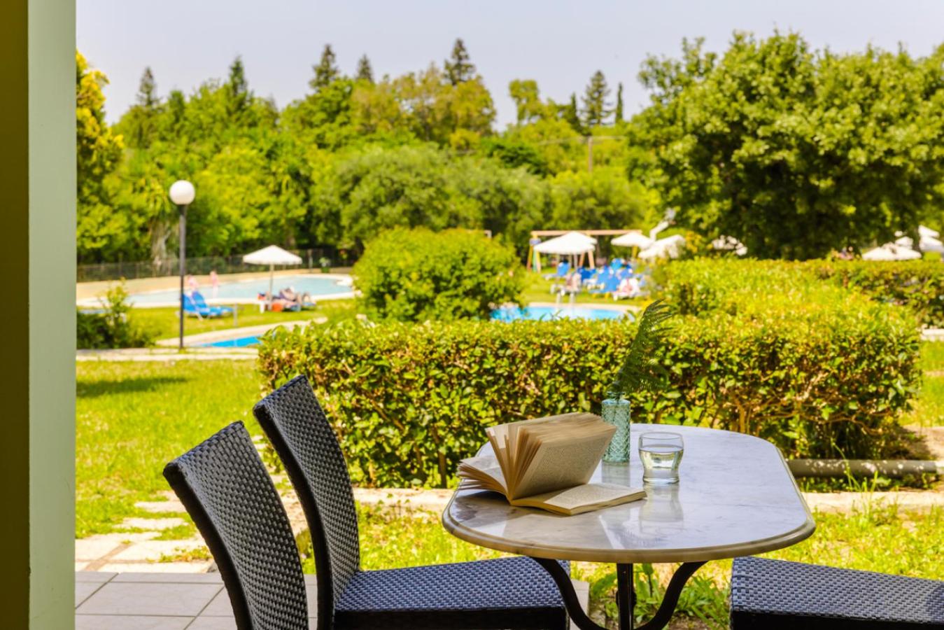 Century Resort Hotel āra terase ar galdiņu un skatu uz baseina zonu un lekno viesnīcas dārzu