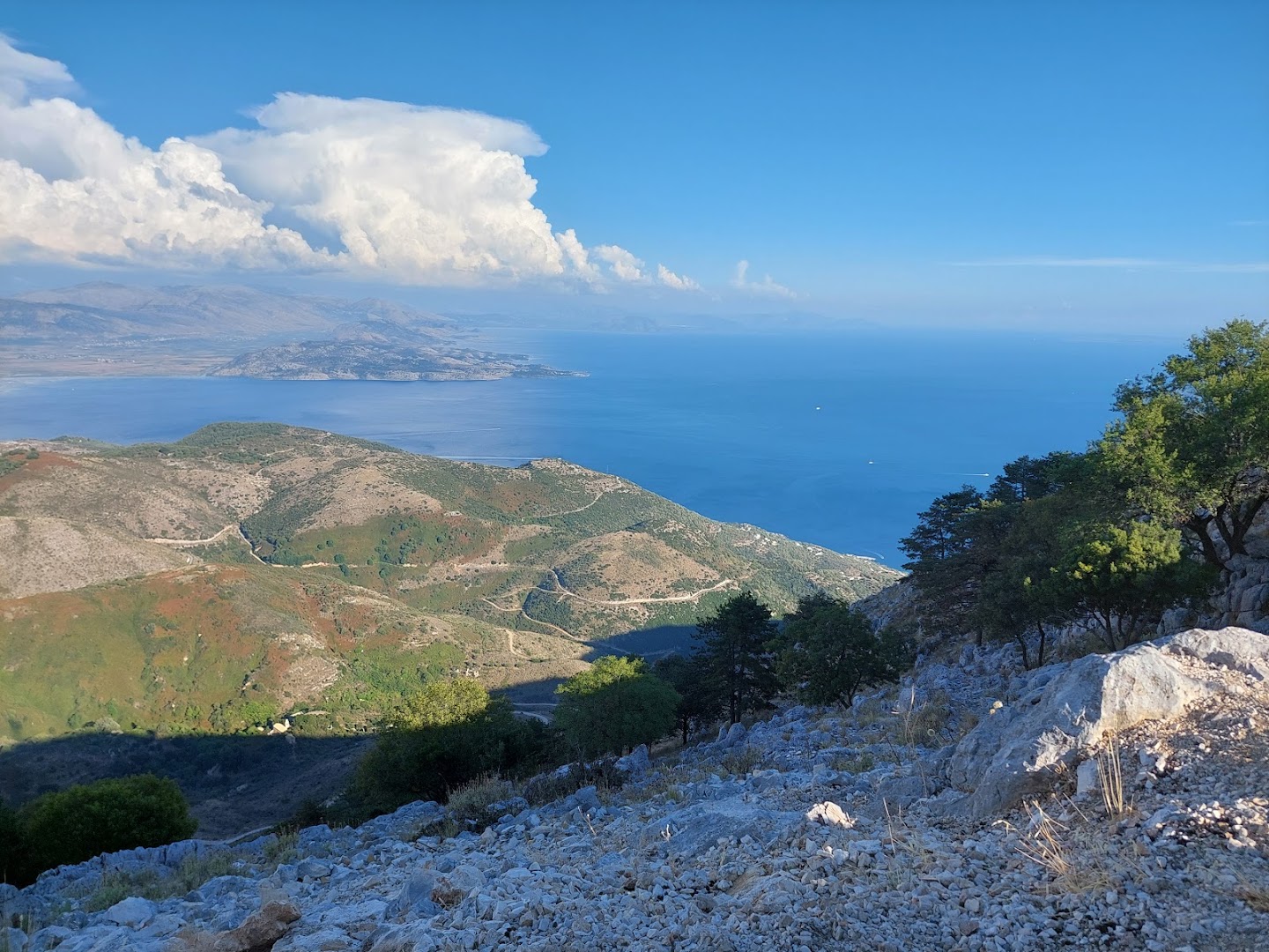 Panorāmas skats no Pantokrator kalna Korfu salā uz Jonijas jūru un piekrastes ciematiem saulainā dienā ar kalnu grēdām