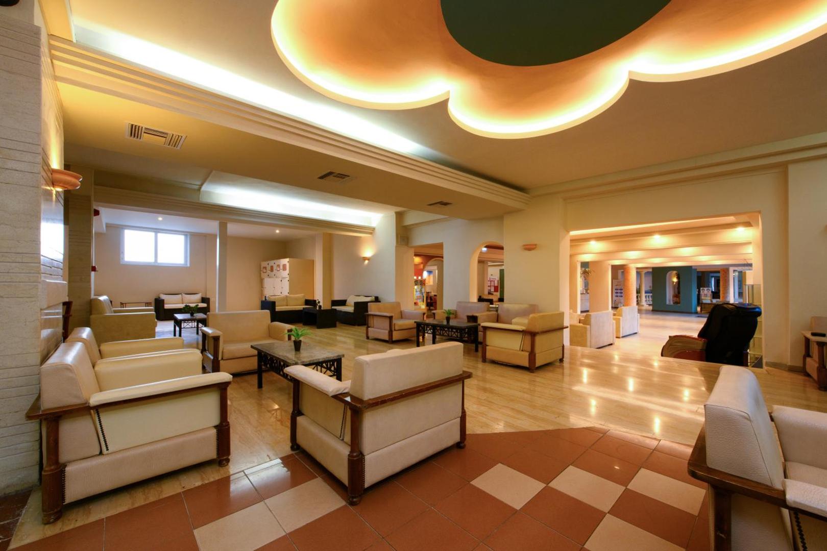 Potamaki Beach viesnīcas lobby zona ar ērtiem atpūtas krēsliem, galdiņiem un siltu apgaismojumu atpūtai piekrastē.